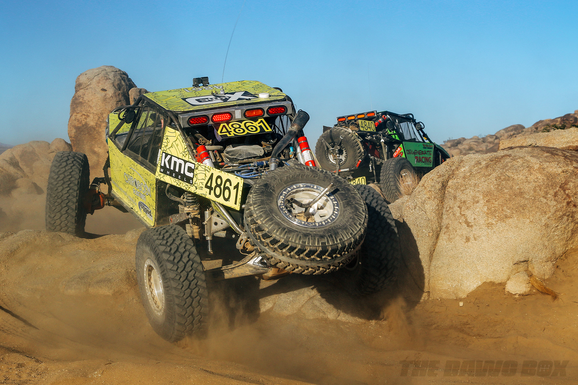 A pair of green rock racers speeding over some boulders
