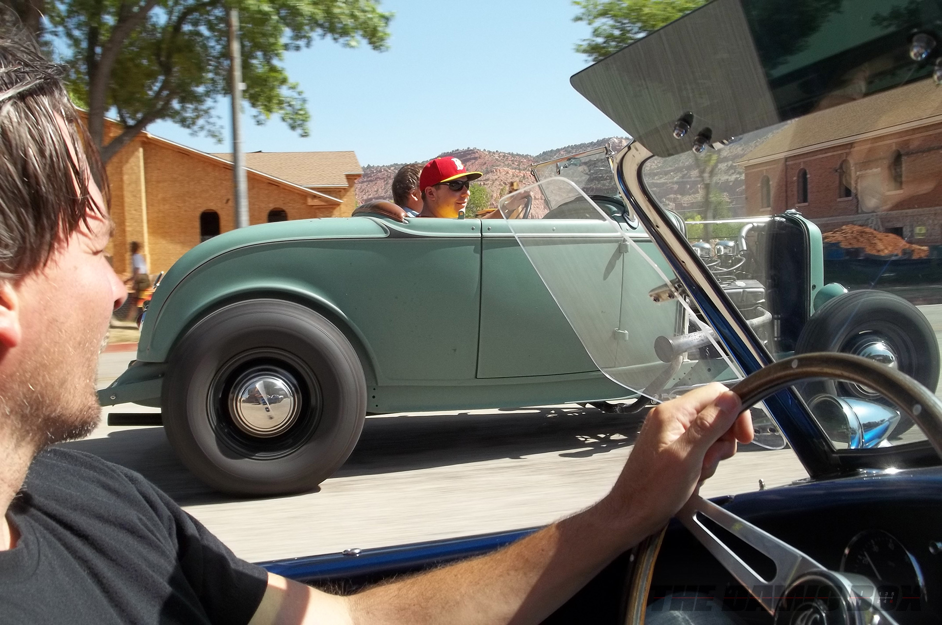 Henry Astor’s ’32 Ford Roadster driving along a road next to a blue Shelby AC Cobra