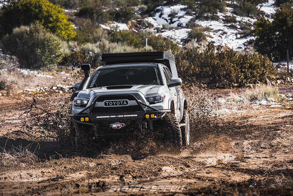 Toyota Tacoma with 35" tires offroad running through the mud