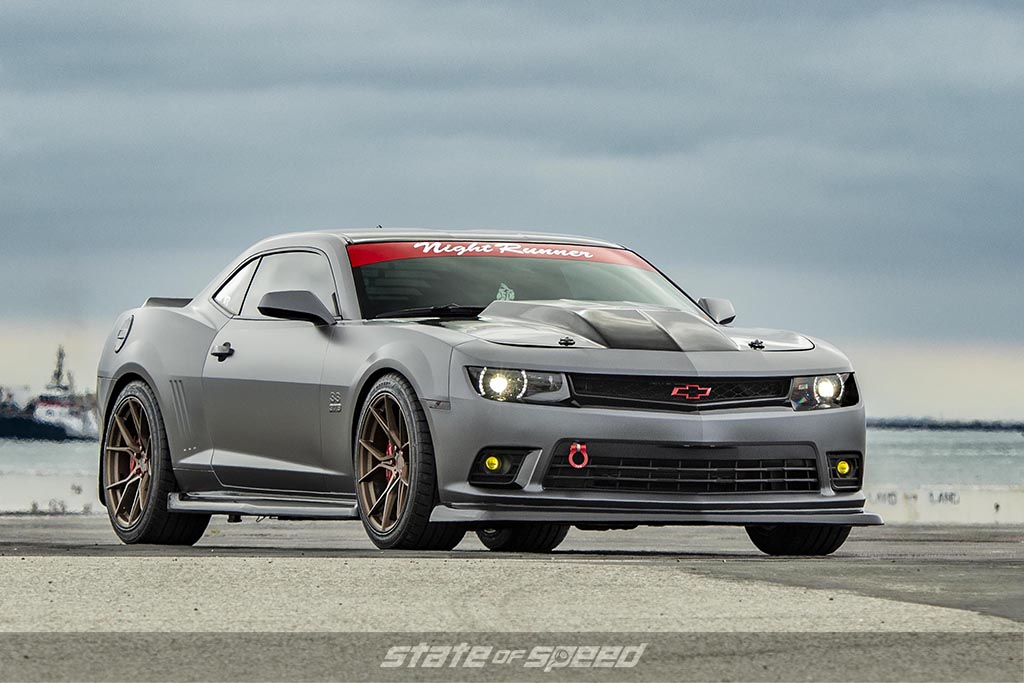 Grey Chevrolet Camaro Sang near some ship docks on a cloudy day