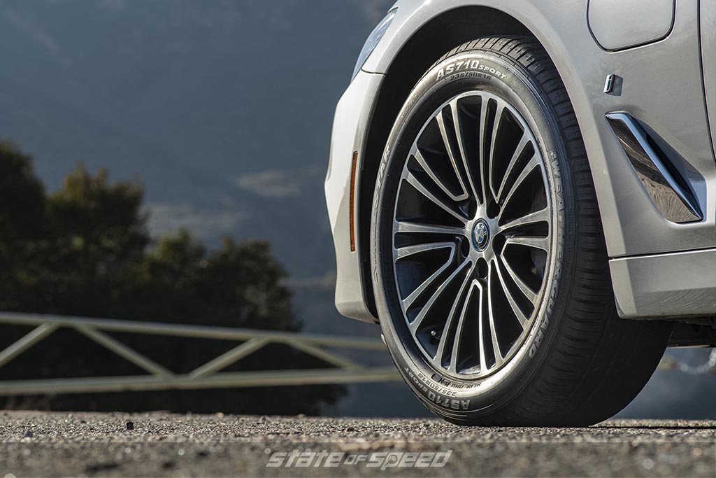 Silver BMW on a road near some mountains