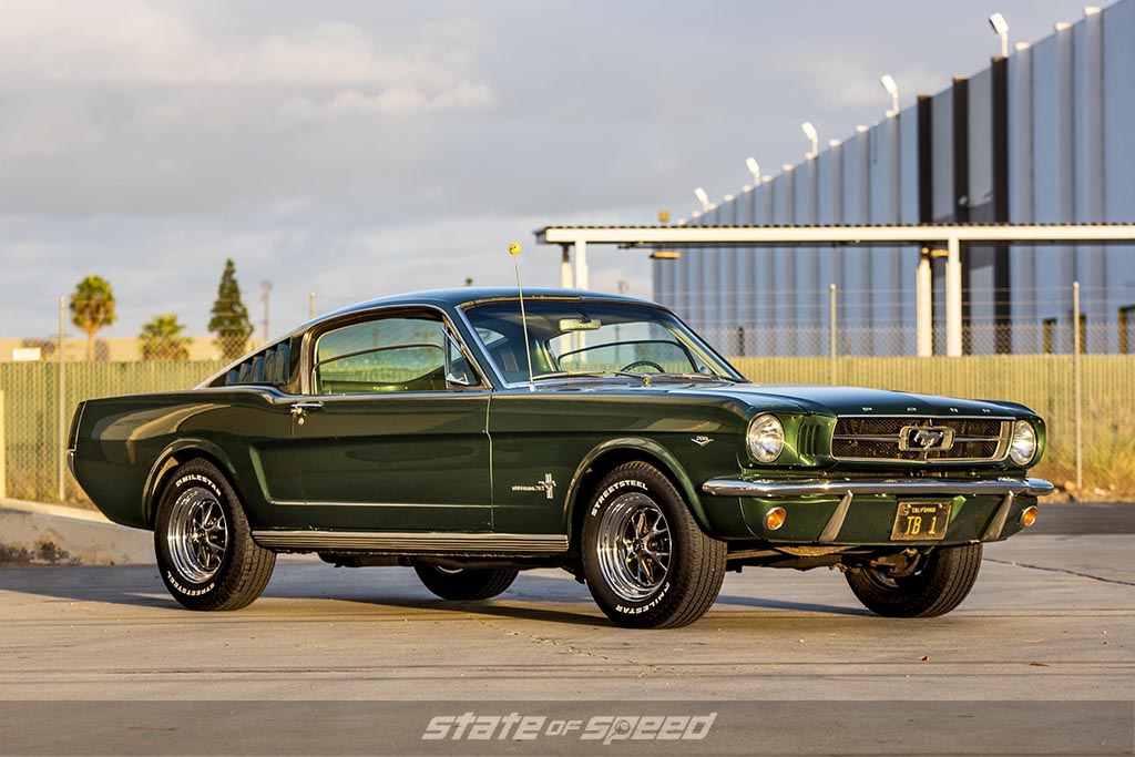 Green 1965 Ford mustang fastback 2+2 on milestar streetsteel tires during a sunset