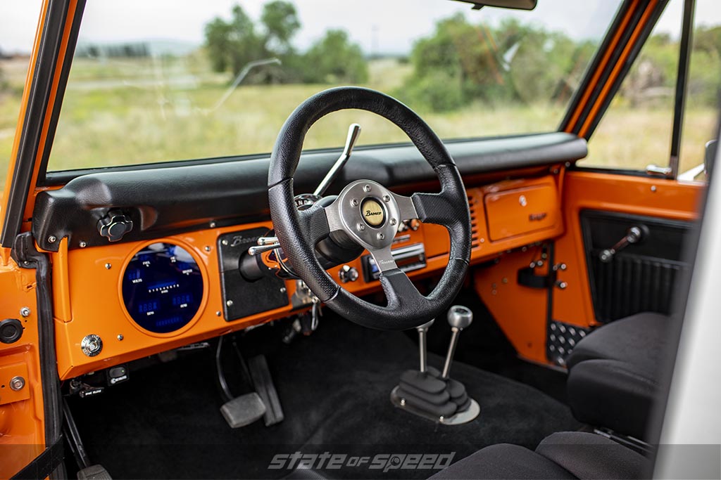 Slightly modernized first generation '76 Ford Bronco Interior in orange with a digital gauge cluster in place of the original speedometer