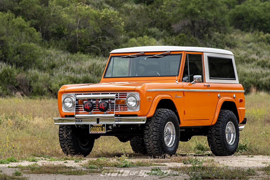 Orange first generation ford bronco on milestar patagonia M/T Tires in a green mountainous area
