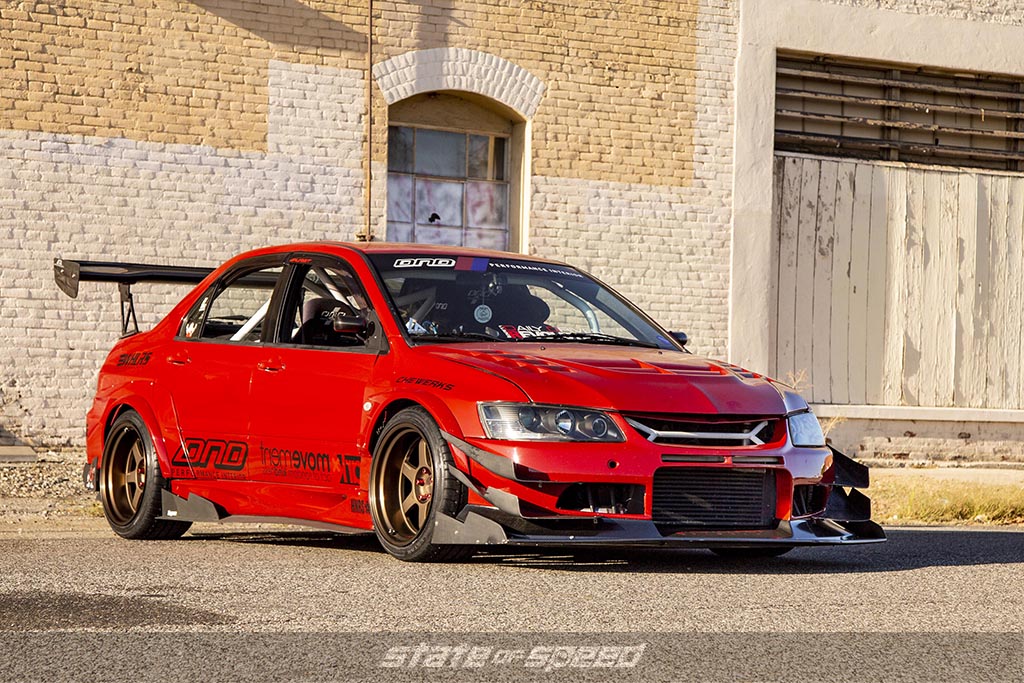 modified Red Mitsubishi Evo on Milestar MS932 XP+ Tires with a rustic background during a sunset